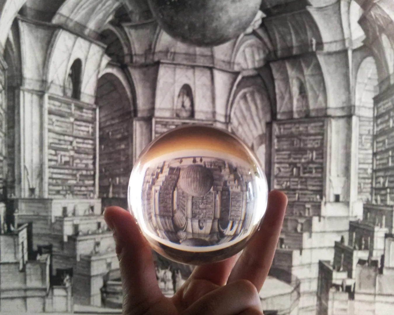 Sfera di cristallo di Elena Lazzara che riflette una biblioteca infinita ispirata alla Biblioteca di Babele